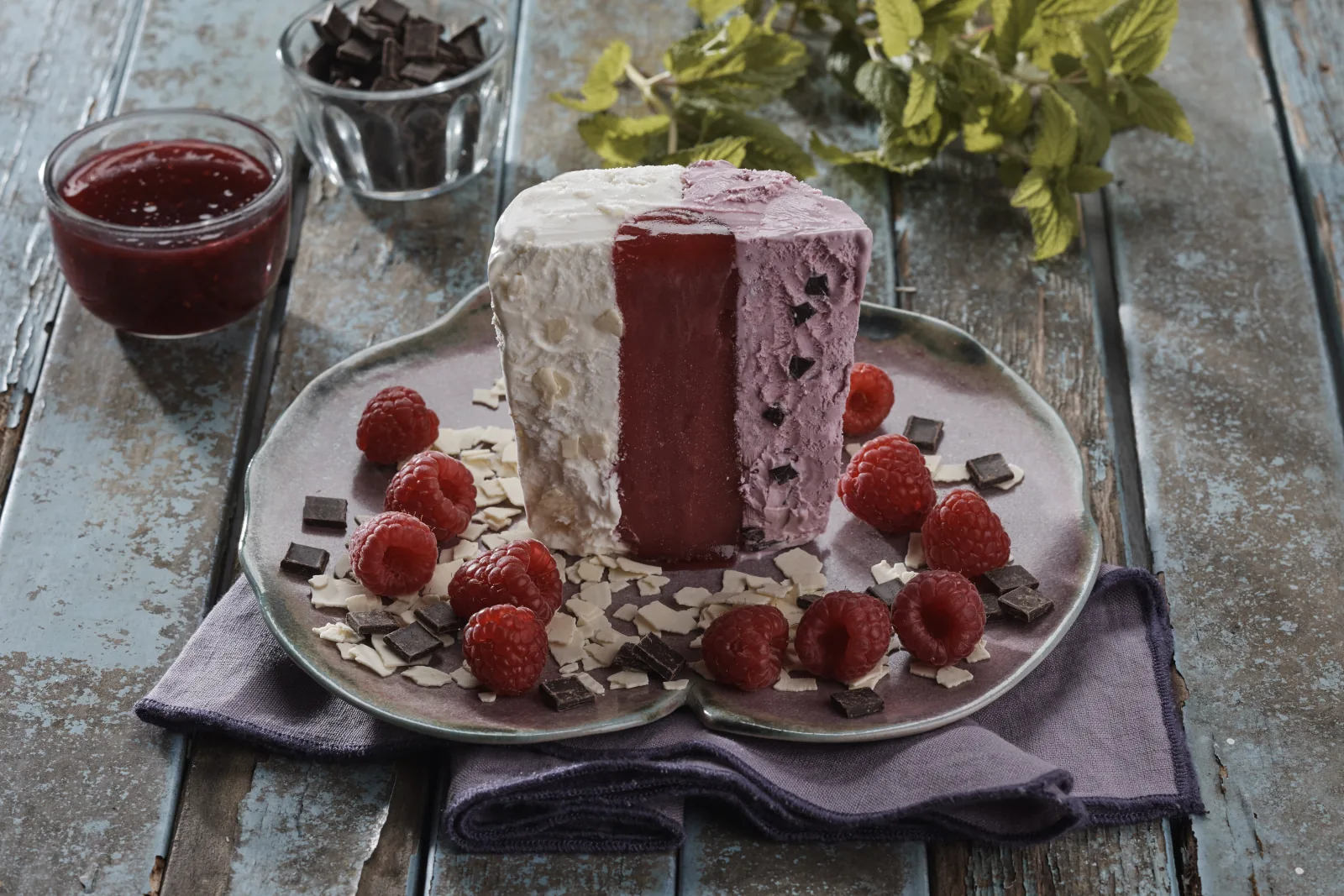 Dreifarbiger Eisblock mit Beerensauce, Himbeeren und Minze garniert